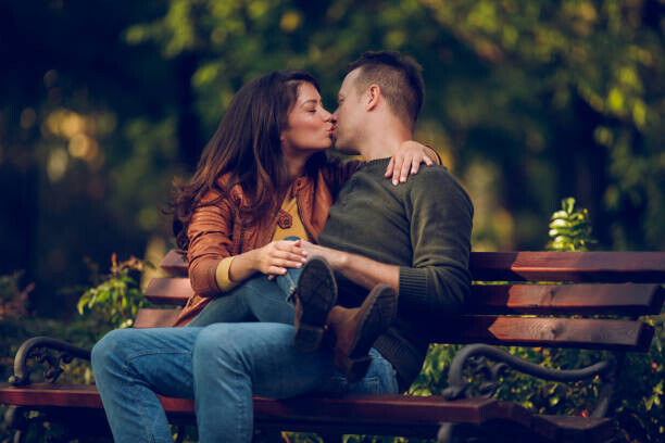 Romantic Couple Kissing On The Bench In The Autumn Park.