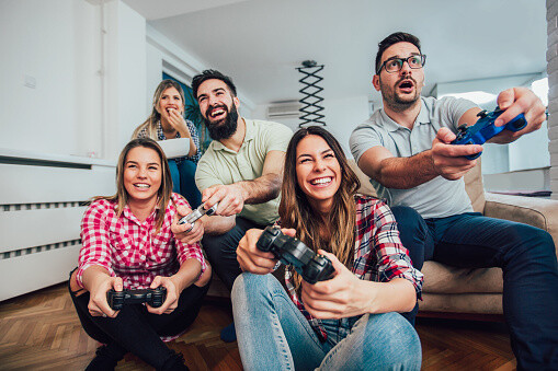Group Of Friends Play Video Games Together At Home, Having Fun.